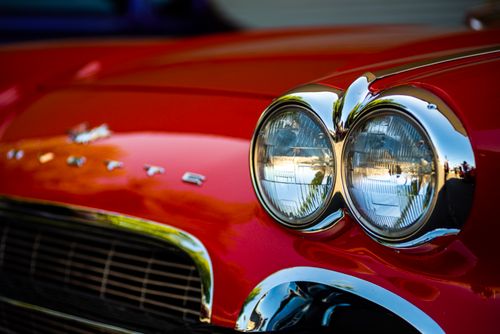Free Detailed close-up of classic red Corvette car headlights showcasing vintage design and chrome details. Stock Photo