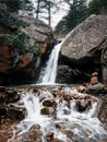 Person Sitting on Rock Near Waterfalls