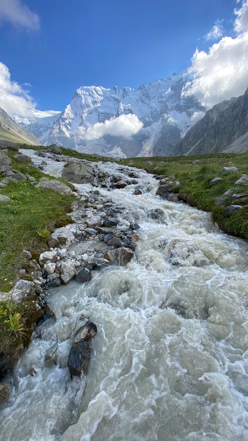 Free A Stream near Snow Capped Mountains Stock Photo