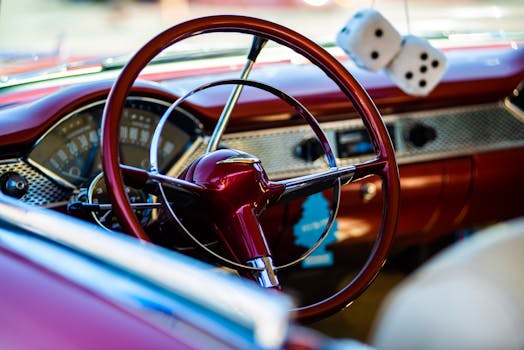 Close-up of a vintage car interior featuring a classic steering wheel and dashboard with fuzzy dice.