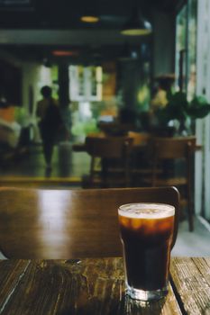 A refreshing cold brew coffee on a wooden table in a cozy cafe environment.