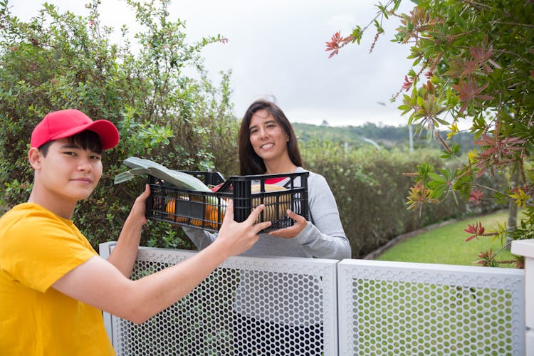 A Delivery Person Handing A Crate Of Produce To A Woman