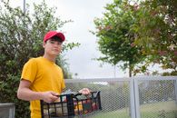 Man in Yellow Crew Neck T-shirt and Red Cap Holding Black Shopping Cart