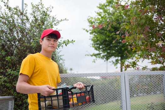 Asian delivery man carrying a plastic basket outdoors in Portugal.