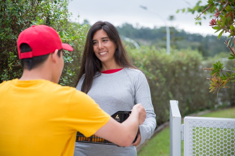 A Delivery Person Handing A Crate Of Produce To A Woman