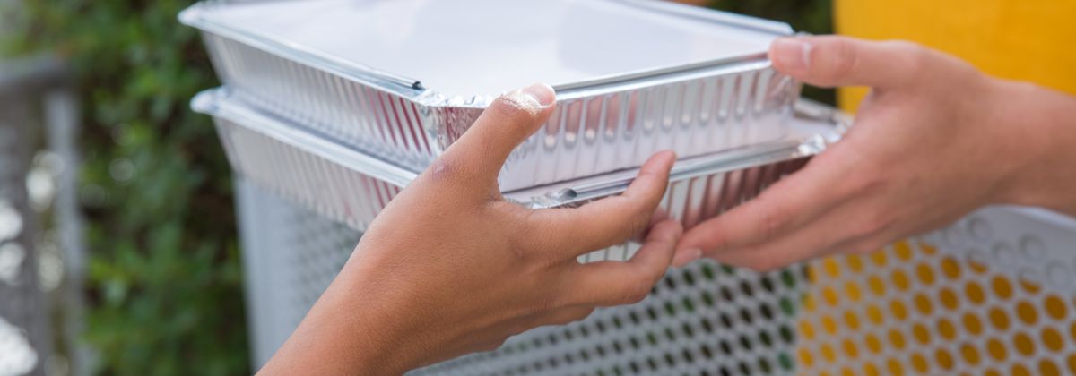 Hands passing a delivered meal container
