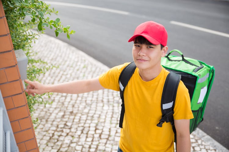 A Delivery Man Clicking The Doorbell While Looking At The Camera