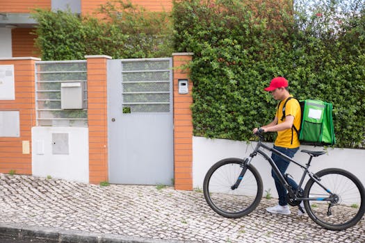 A bicycle courier in casual attire delivers a package at a residential area.
