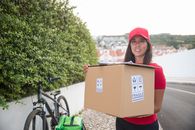 Woman in Red Cap Holding Brown Cardboard Box