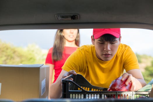 Man in yellow shirt loading groceries into a vehicle, outdoors.