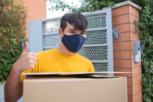 Man Wearing a Yellow T-shirt Carrying a Box