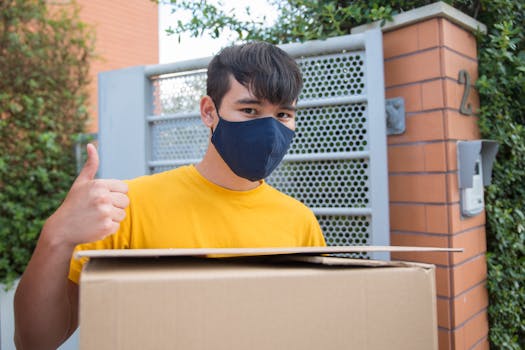 Man in a facemask delivers a package with a thumbs up outside a house in Portugal, showcasing contactless delivery.
