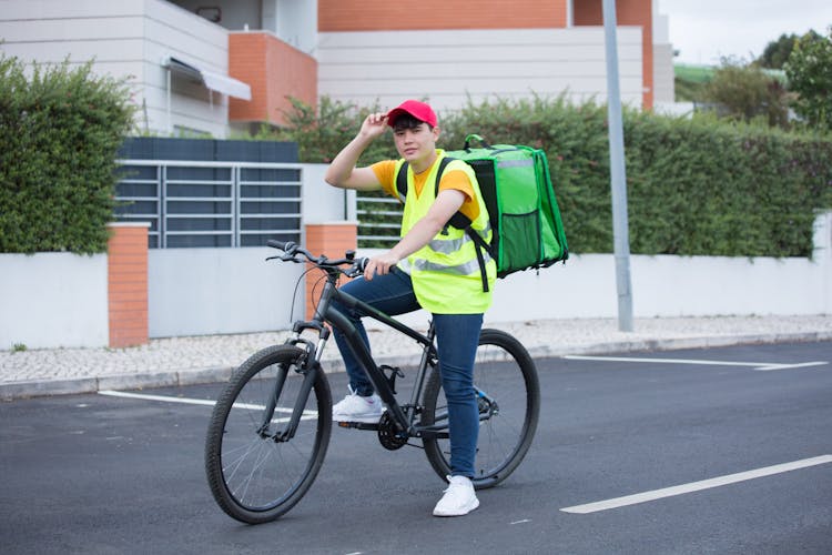 A Delivery Man Carrying An Insulated Bag While Riding On A Bicycle