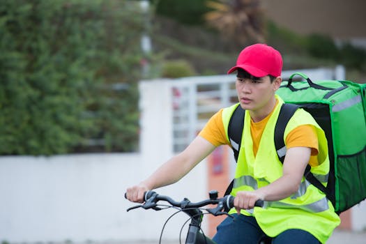 Bicycle delivery person in high visibility gear cycling on a street in Portugal.