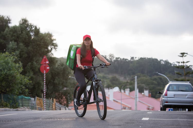 A Woman Riding A Bike With Food Delivery  Bag