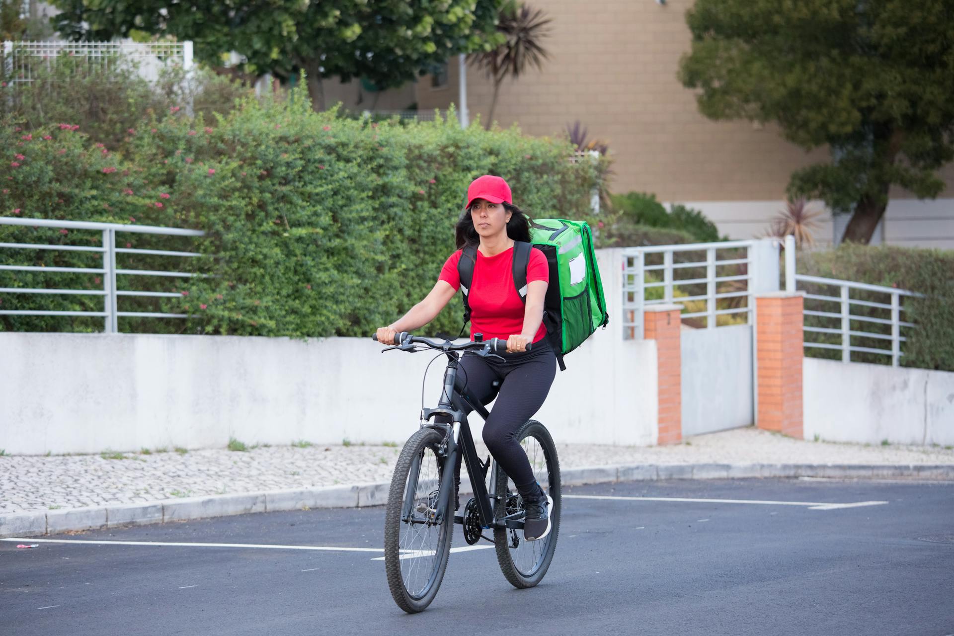 A Delivery Woman Riding on a Bicycle while Carrying an Insulated Bag