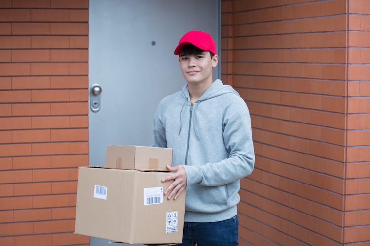 Man Wearing Gray Hoodie Carrying Boxes