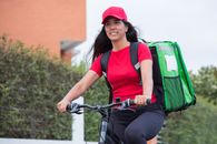 Woman in Red Tank Top and Green Jacket Riding on Green Bicycle