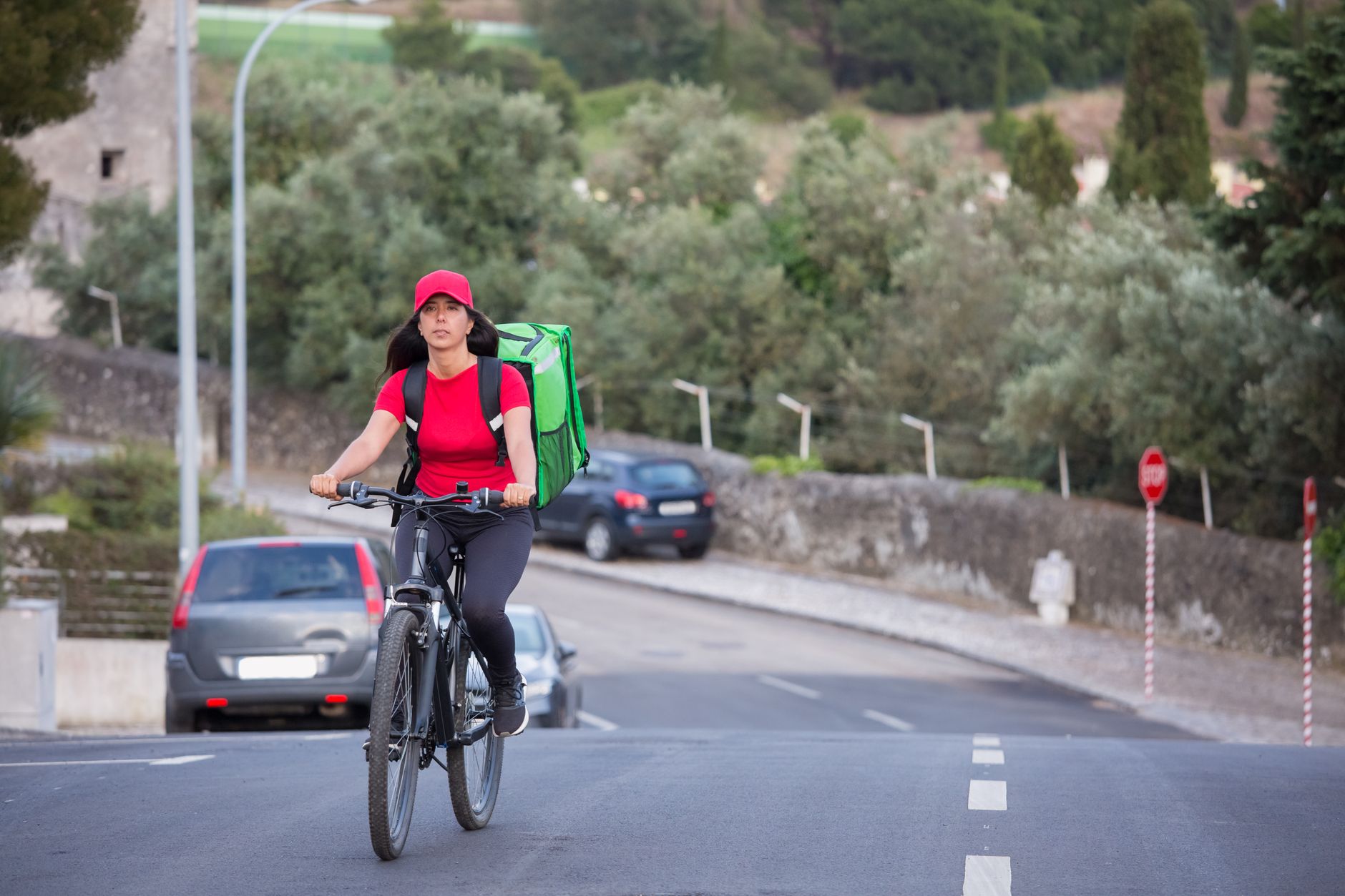 Asian woman delivering packages by bicycle on a city street in Portugal.