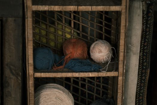 Vibrant yarn balls in rustic wooden shelf setting, capturing the essence of crafting materials.
