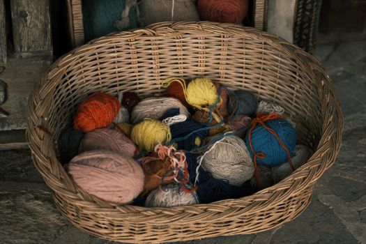A variety of colorful yarns in a woven basket, perfect for knitting or crafts.