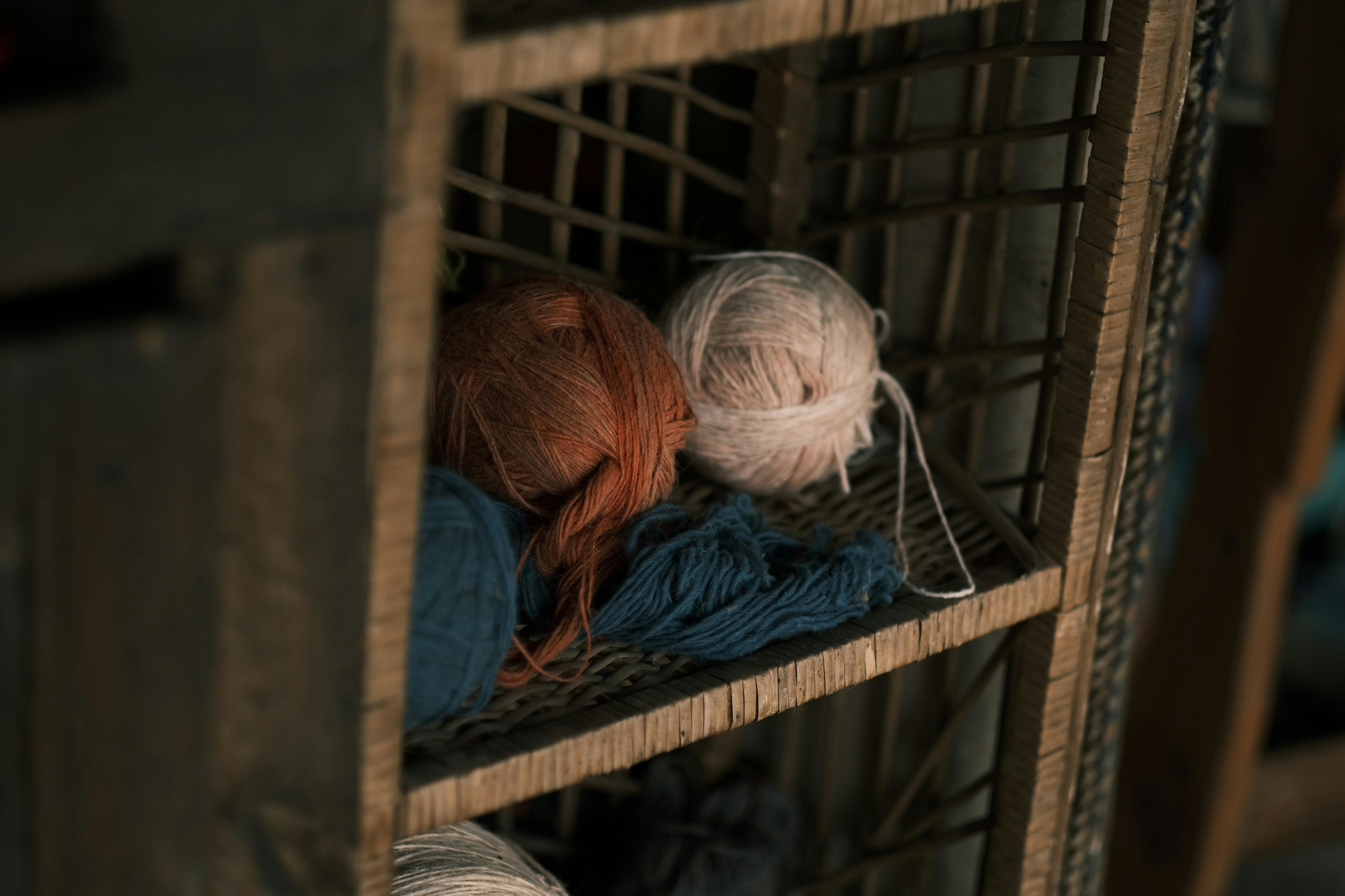 Close-up of vibrant yarn balls on a rustic wooden shelf, perfect for knitting enthusiasts.