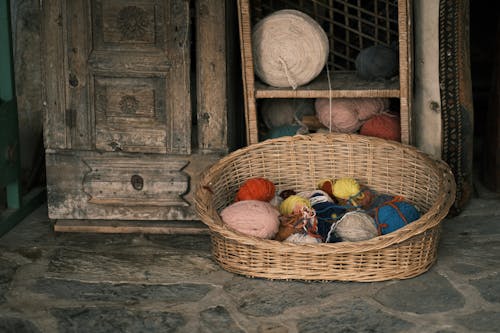 Sewing Threads on the Shelf and Woven Basket Beside the Wooden Cabinet