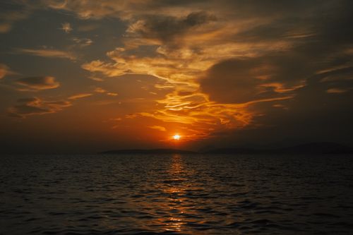 Free Captivating sunset over the ocean with glowing orange sky and calm water. Stock Photo