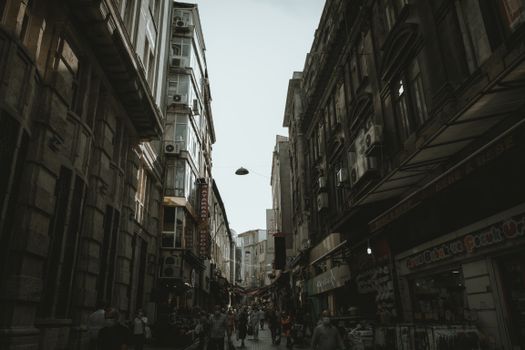 Explore the vibrant life of a busy urban alley with tall historical buildings and bustling pedestrians.