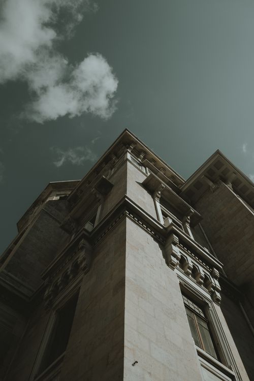 Free Capture of a majestic building from a low angle showing intricate architectural details against a sky. Stock Photo
