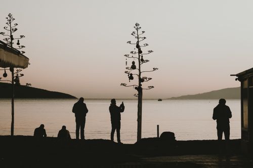 Free Silhouettes of people by the sea during a serene dusk, capturing a peaceful moment. Stock Photo