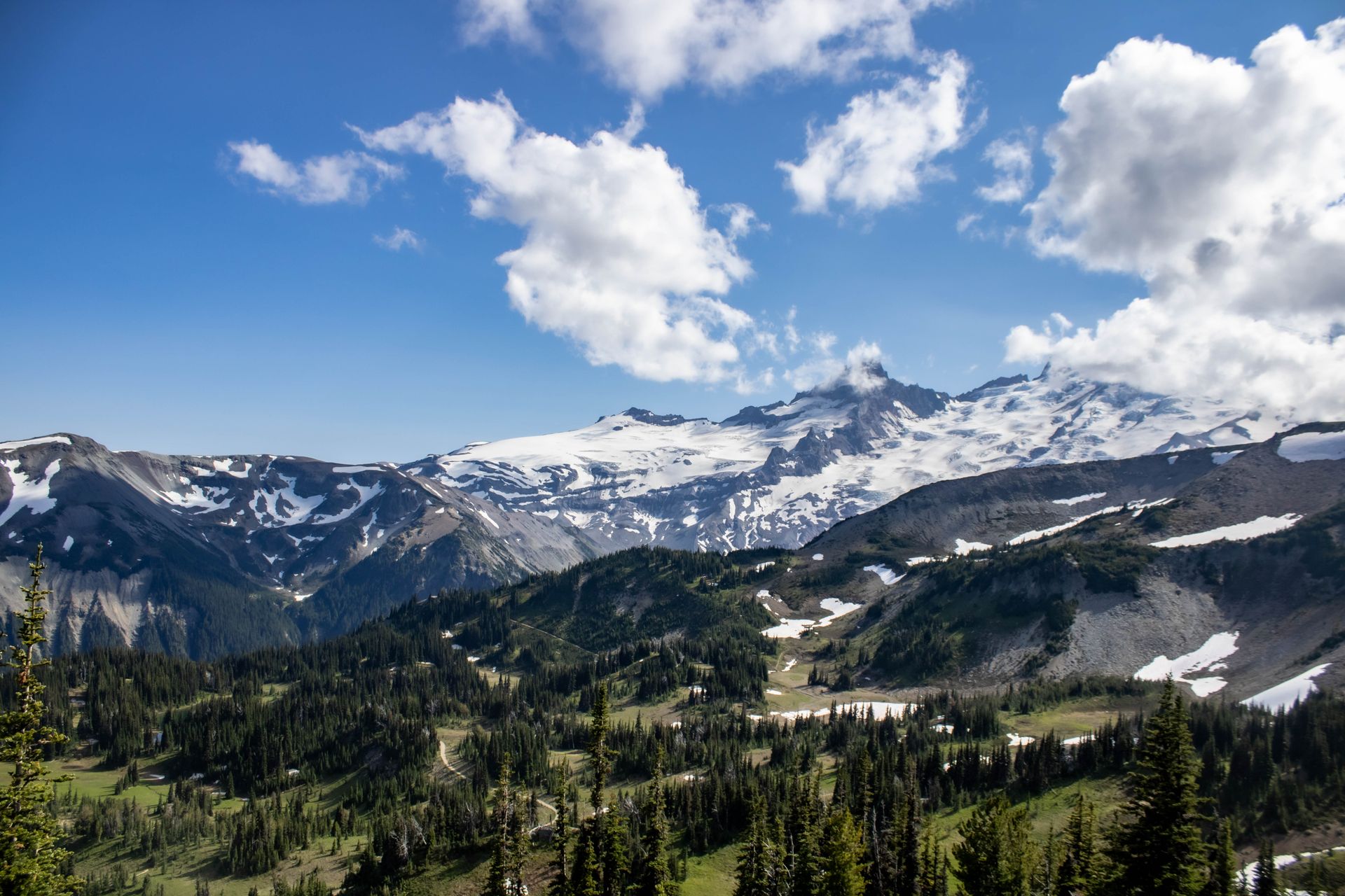 A breathtaking view of Mount Rainier covered in snow under a bright blue sky with clouds.
