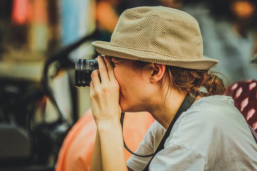 Free A woman photographer with a hat using a camera to capture candid street moments in New York. Stock Photo