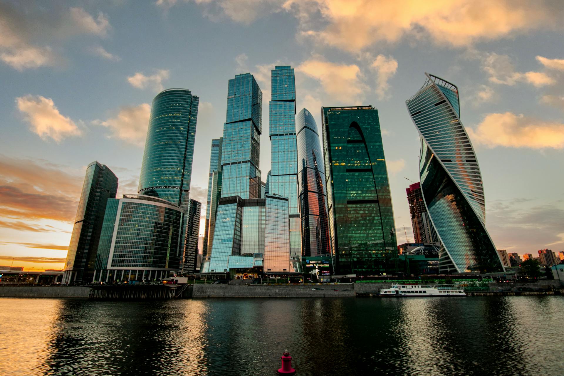 Stunning skyline of Moscow City with modern skyscrapers reflecting in the river at sunset.