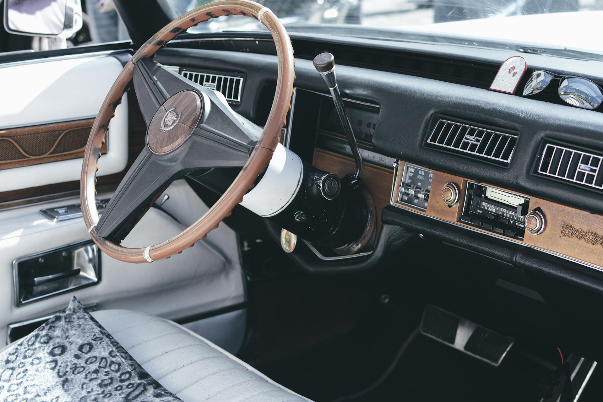 Close-up of a vintage car's dashboard showcasing the wooden steering wheel and classic interior elements.