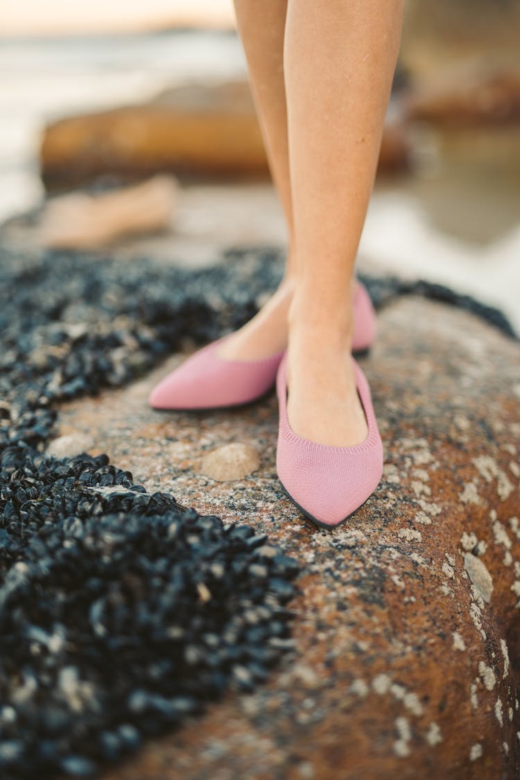 A Woman Wearing A Pink Sandals Standing On Rocks