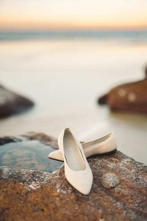 White Leather Flats on Brown Rock