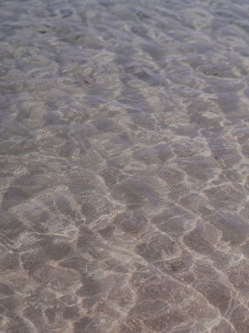Free Close-up of rippling clear sea water on a sandy beach, capturing natural patterns. Stock Photo