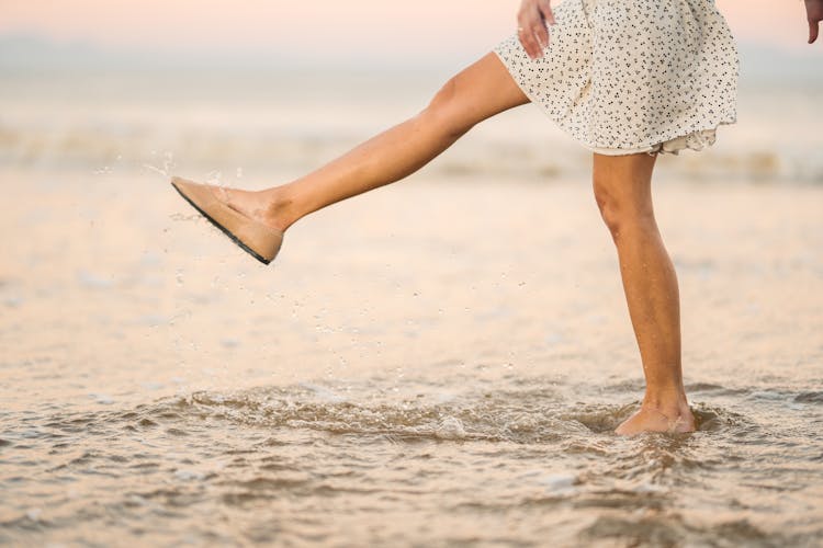 A Woman Wetting Her Sandals In The Beach