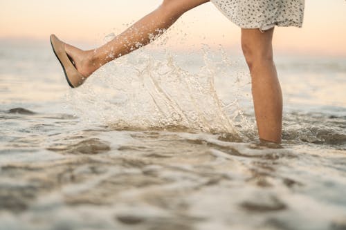 Person Wearing Floral Dress Kicking the Ocean 