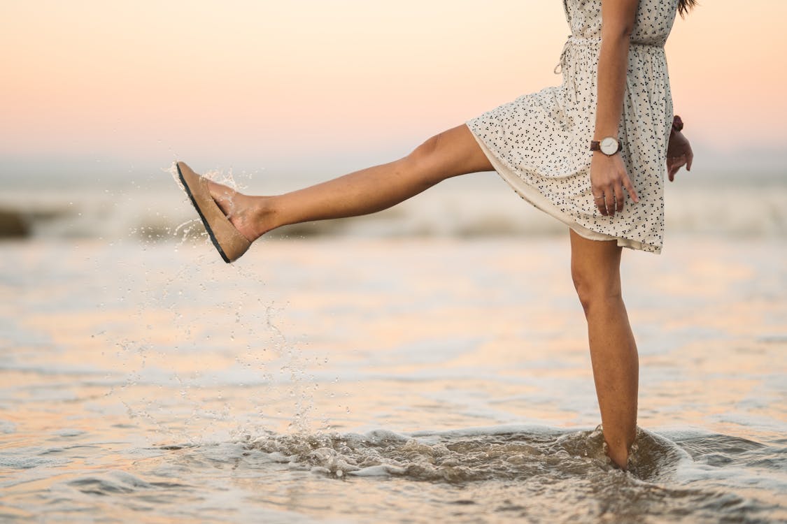 Woman in a Dress Kicking Water at the Beach
