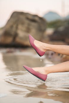 Stylish pink shoes on legs, captured near a serene water reflection, conveying calm.