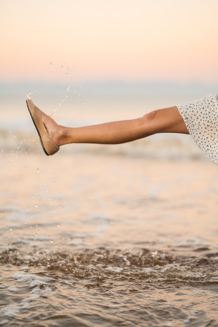 A Woman In The Beach Wearing Wet Sandals