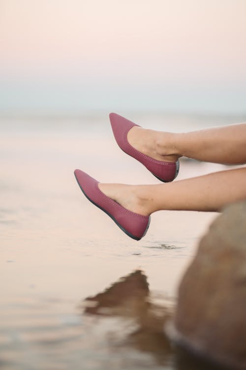 A Woman Wearing Pink Slip on Shoes in the Beach