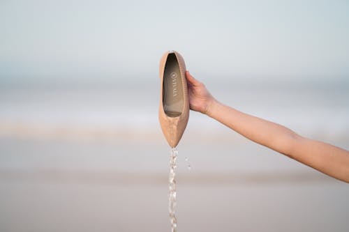 Person Holding a Wet Brown Flat Shoe 
