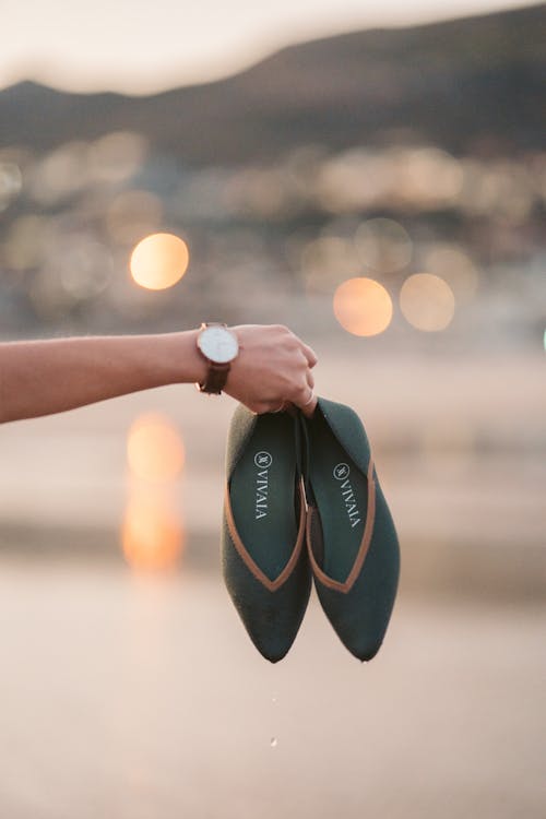 Person Holding Green and Brown Flip Flops