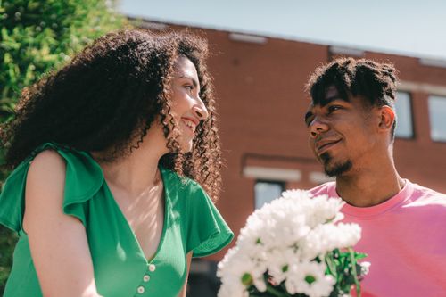 Free Happy couple in love sharing a tender moment with a bouquet of flowers outdoors. Stock Photo