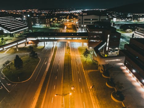Aerial view of a well-lit urban area at night, showcasing streets, buildings, and city lights.