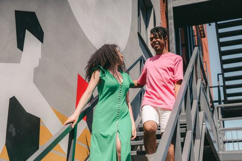 Free Happy couple walking down stairs, showcasing love and modern style. Stock Photo