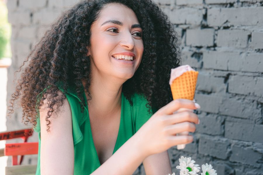 Mujer riendo con un cono de helado de fresa